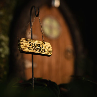 Close-up of hand-painted fairy door showing climbing vine details, weathered wood texture, and tiny brass-style knob
