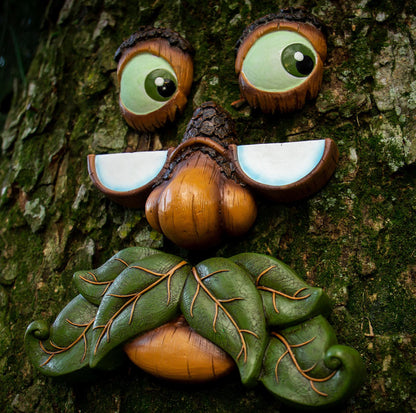 Close-up of whimsical tree face sculpture showing expressive eyes, nose, and mouth with natural brown and green tones