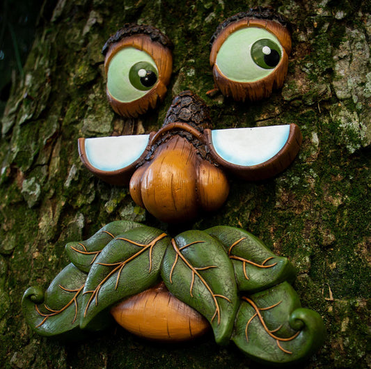 Close-up of whimsical tree face sculpture showing expressive eyes, nose, and mouth with natural brown and green tones