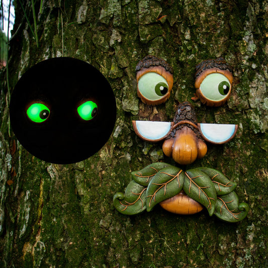 Hand-painted glow in the dark old man tree face mounted on a large outdoor tree trunk in a garden yard