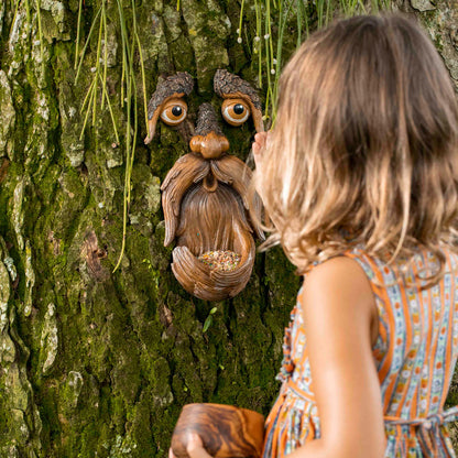 Tree face bird feeder shown from a low angle on a tree, illustrating how it blends into natural bark surroundings