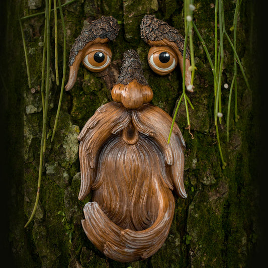 Hand-painted tree face bird feeder mounted on a tree trunk with a small bird perched on the seed tray