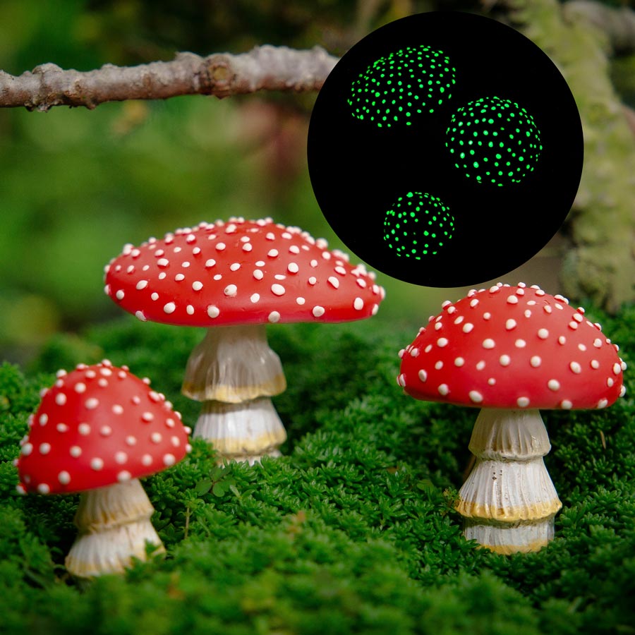 Group of hand-painted polyresin mushroom garden figurines arranged at the base of a tree in an outdoor garden